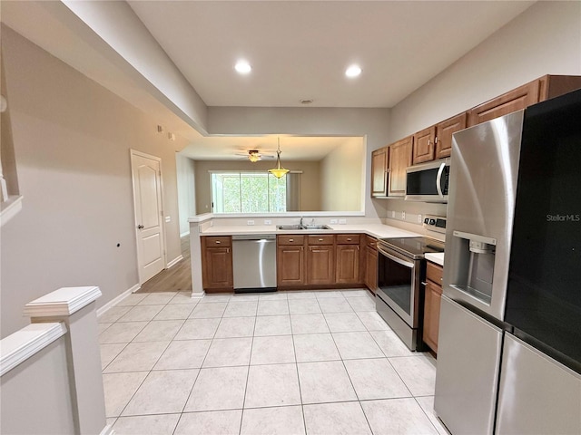 26514 Chimney Spire Ln, Wesley Chapel, FL 33544 - kitchen featuring stainless steel appliances, light countertops, brown cabinetry, light tile patterned floors, and recessed lighting