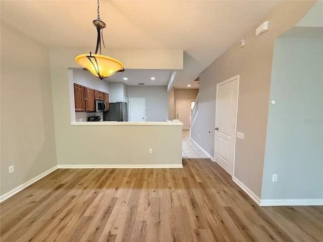 26514 Chimney Spire Ln, Wesley Chapel, FL 33544 - kitchen with stainless steel appliances, light wood-type flooring, decorative light fixtures, baseboards, and a peninsula