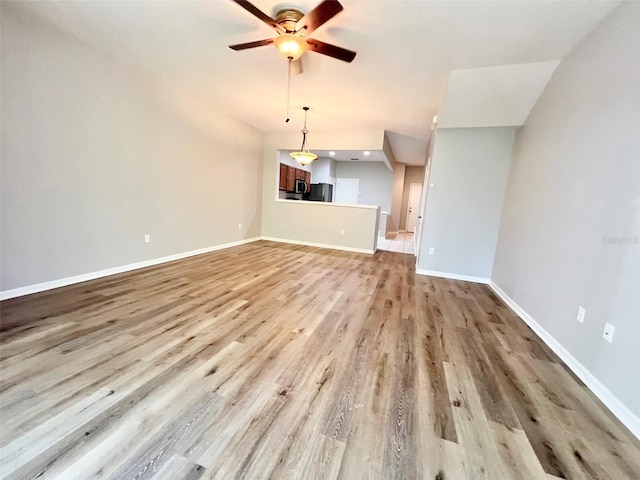26514 Chimney Spire Ln, Wesley Chapel, FL 33544 - unfurnished living room featuring a ceiling fan, light wood-style floors, and baseboards