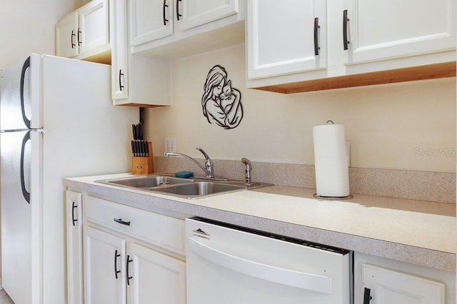 kitchen with light countertops, a sink, white cabinetry, and white appliances
