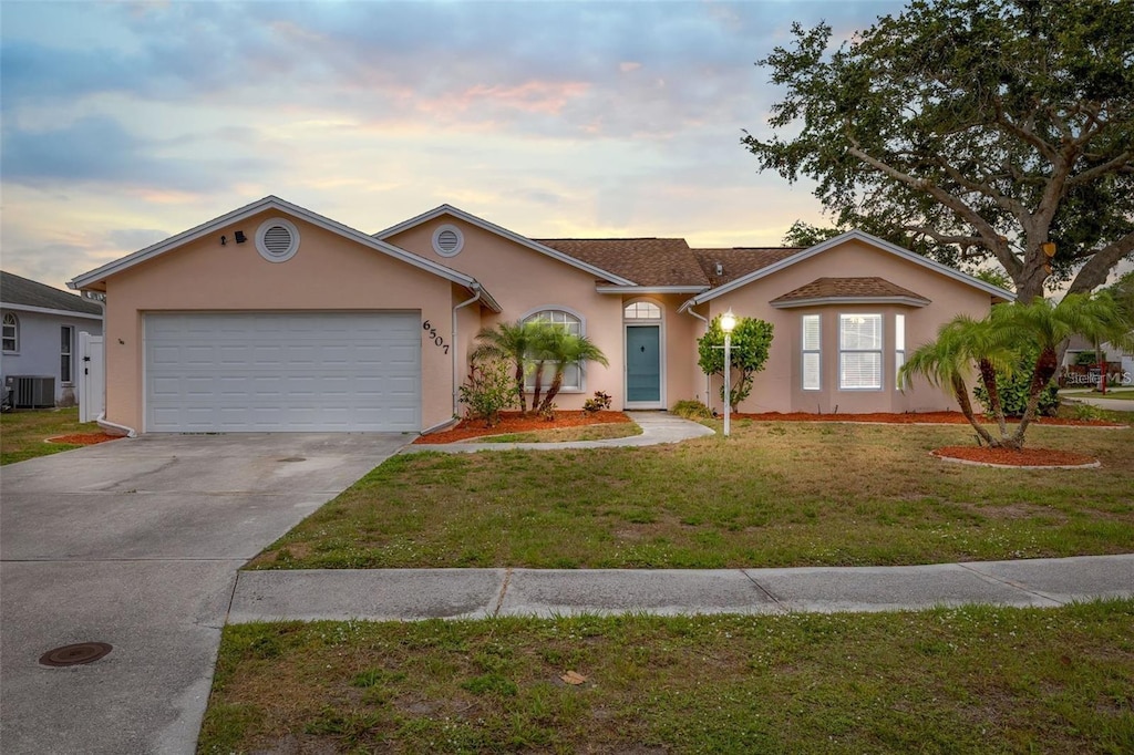 6507 61st Dr E, Palmetto, FL 34221 - ranch-style house featuring an attached garage, stucco siding, a front yard, central AC unit, and concrete driveway