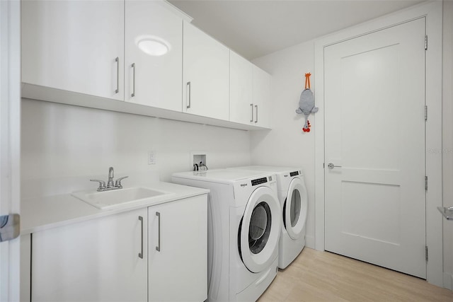 301 1st St S Unit 2305, Saint Petersburg, FL 33701 - clothes washing area with light wood-style floors, washer and clothes dryer, cabinet space, and a sink