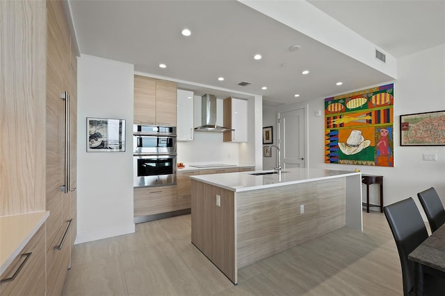 301 1st St S Unit 2305, Saint Petersburg, FL 33701 - kitchen featuring wall chimney range hood, a sink, light countertops, modern cabinets, and a center island with sink