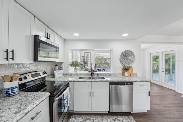 kitchen with a sink, appliances with stainless steel finishes, white cabinets, and dark wood finished floors