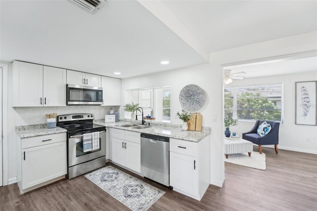 kitchen with white cabinets, a sink, stainless steel appliances, wood finished floors, and visible vents