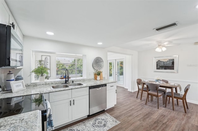 kitchen featuring visible vents, wood finished floors, light stone countertops, a sink, and appliances with stainless steel finishes