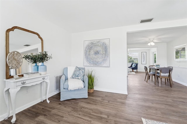 sitting room with visible vents, a ceiling fan, baseboards, and wood finished floors