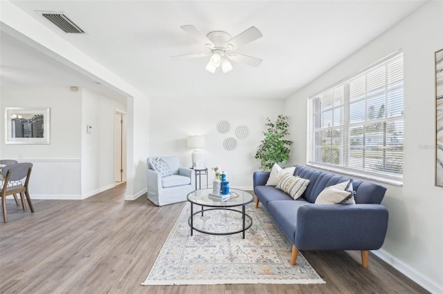 living area with baseboards, ceiling fan, visible vents, and wood finished floors