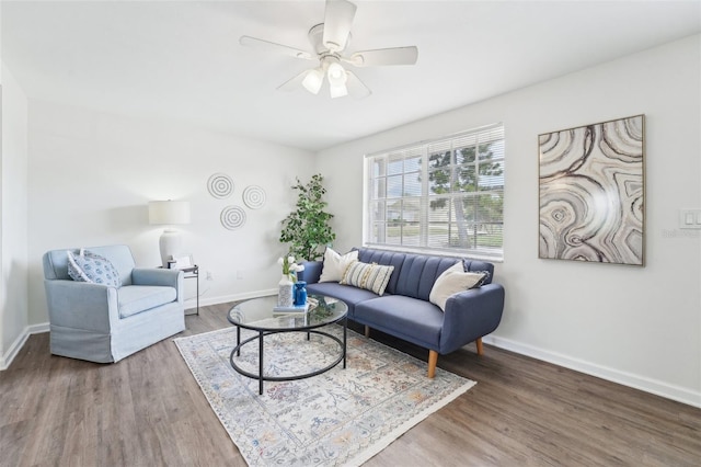 living room featuring a ceiling fan, baseboards, and wood finished floors