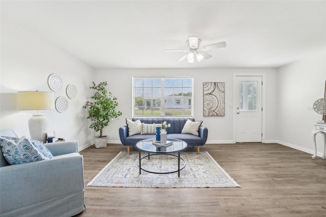 living area with a ceiling fan, baseboards, plenty of natural light, and wood finished floors