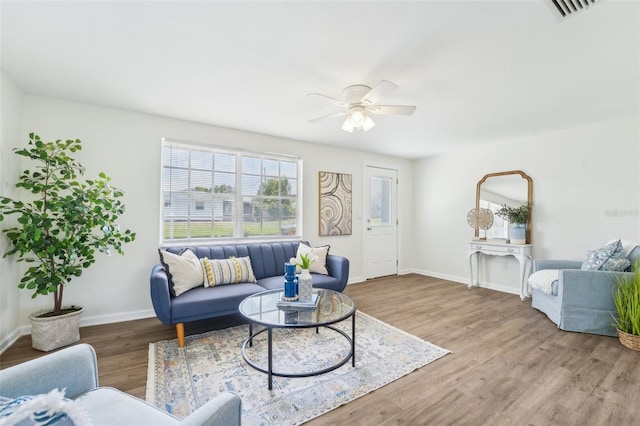 living area featuring visible vents, baseboards, ceiling fan, and wood finished floors