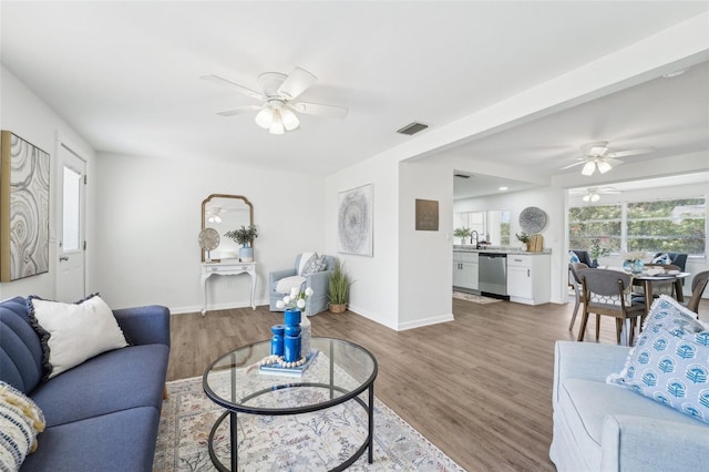 living room with a ceiling fan, baseboards, visible vents, and light wood-type flooring