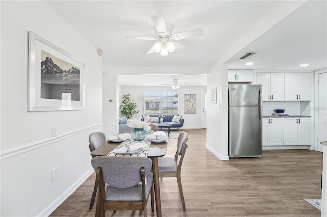 dining area with ceiling fan, visible vents, baseboards, and wood finished floors