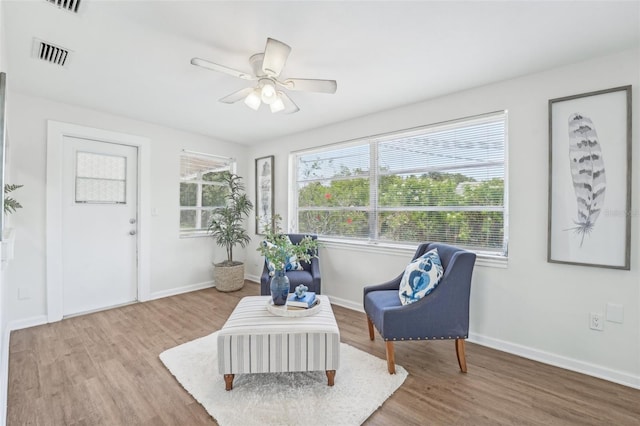 living area featuring visible vents, baseboards, and wood finished floors