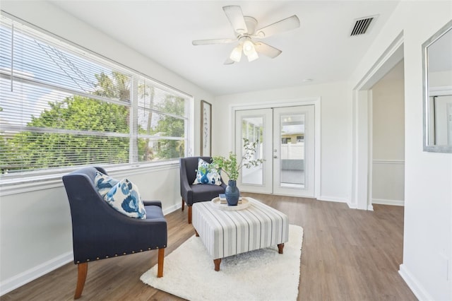 sitting room featuring a ceiling fan, baseboards, visible vents, and wood finished floors