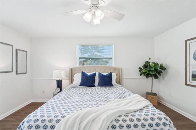 bedroom featuring wainscoting, baseboards, a ceiling fan, and dark wood finished floors