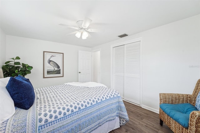 bedroom with visible vents, a closet, baseboards, dark wood-style floors, and a ceiling fan