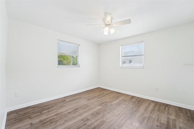 unfurnished room featuring baseboards, wood finished floors, and a healthy amount of sunlight