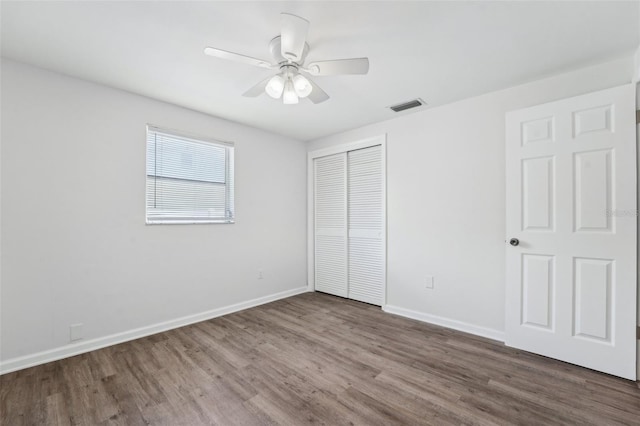 unfurnished bedroom with baseboards, a closet, wood finished floors, and visible vents