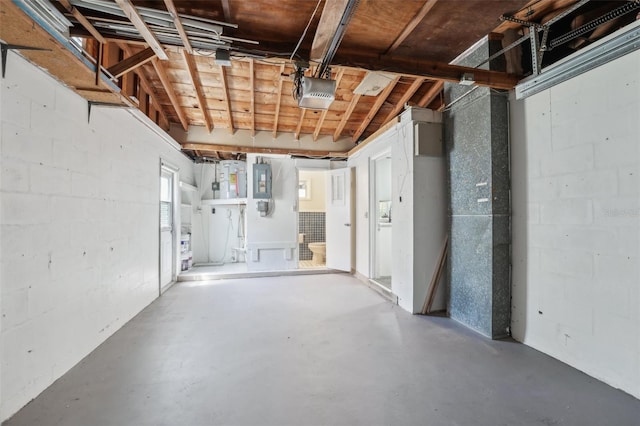 basement featuring a garage, concrete block wall, and electric panel