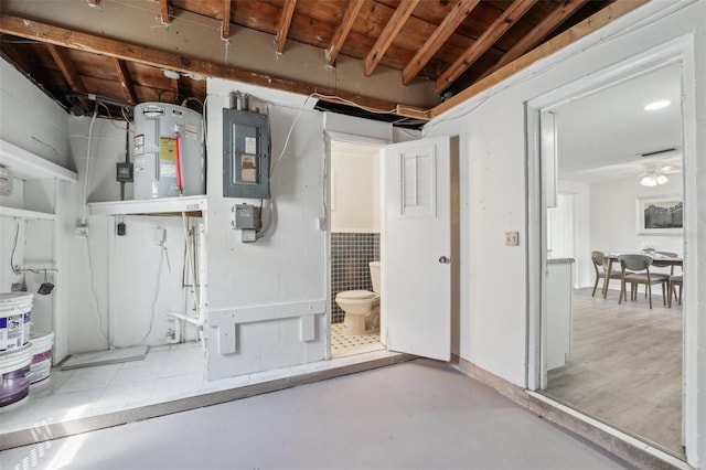 basement with a ceiling fan, visible vents, water heater, and electric panel