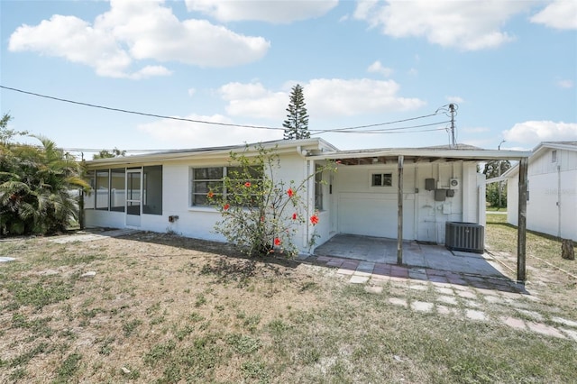 ranch-style home featuring a sunroom, central AC unit, a front lawn, and concrete block siding