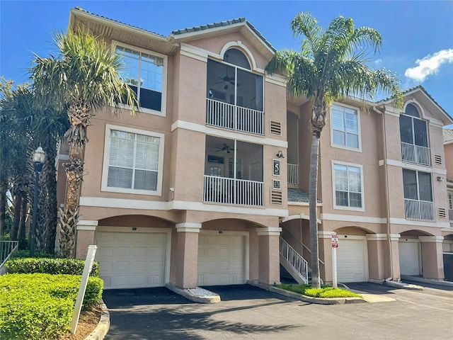 townhome / multi-family property featuring stucco siding, stairway, driveway, a balcony, and an attached garage