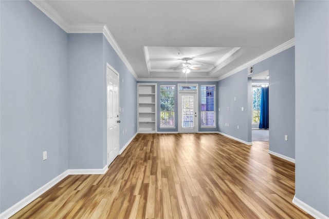 unfurnished living room featuring a raised ceiling, wood finished floors, built in features, and baseboards