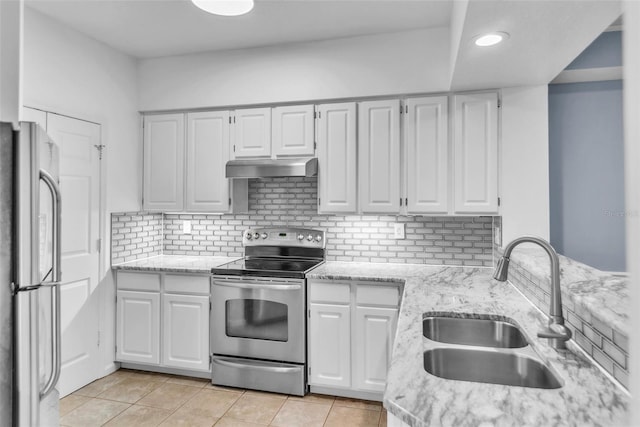 kitchen with light stone counters, stainless steel appliances, under cabinet range hood, backsplash, and a sink