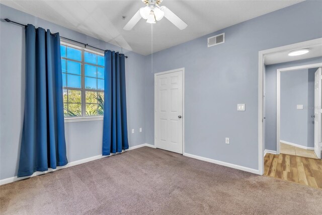 carpeted spare room featuring visible vents, ceiling fan, and baseboards