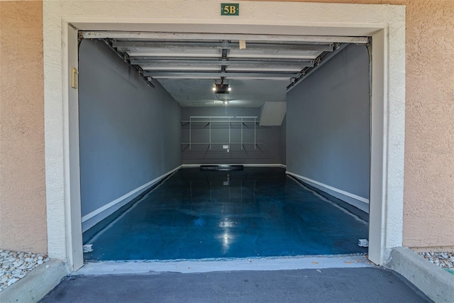 garage featuring a textured wall, a garage door opener, and baseboards