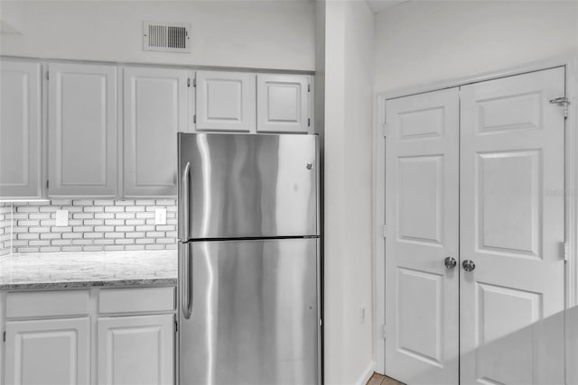 kitchen with white cabinetry, visible vents, and freestanding refrigerator