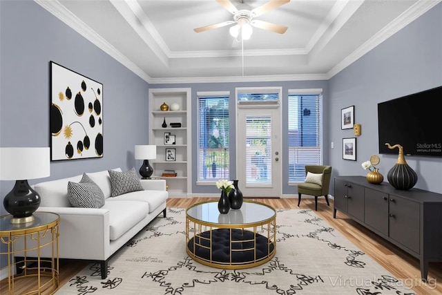 living room featuring wood finished floors, a raised ceiling, ceiling fan, and built in shelves