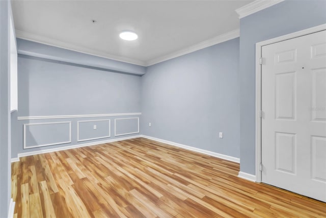 spare room featuring baseboards, light wood-style flooring, and crown molding