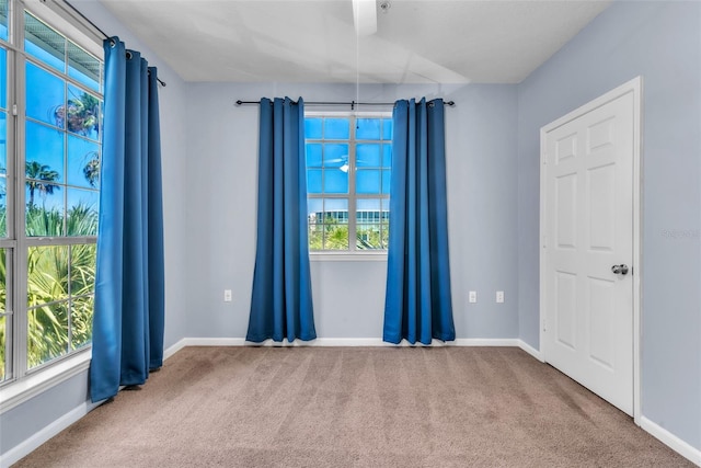 carpeted spare room featuring a wealth of natural light and baseboards