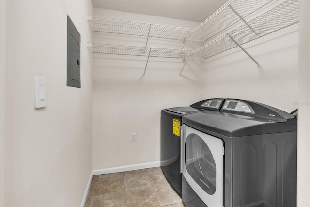 laundry room featuring washing machine and clothes dryer, electric panel, laundry area, baseboards, and tile patterned flooring