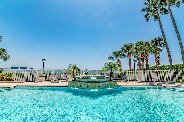 pool with fence and a hot tub