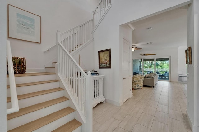 staircase with baseboards and a ceiling fan