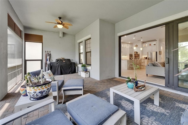 interior space with an outdoor hangout area, ceiling fan, and a healthy amount of sunlight