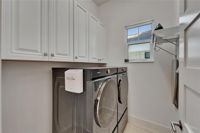 washroom with cabinet space, baseboards, and washing machine and dryer
