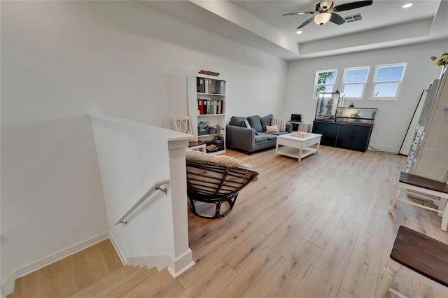 living room with ceiling fan, light wood-style flooring, recessed lighting, a tray ceiling, and visible vents