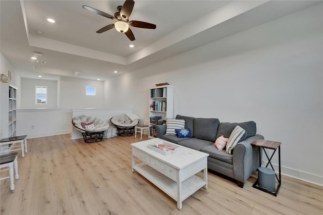 living room featuring recessed lighting, ceiling fan, a tray ceiling, and light wood-style floors