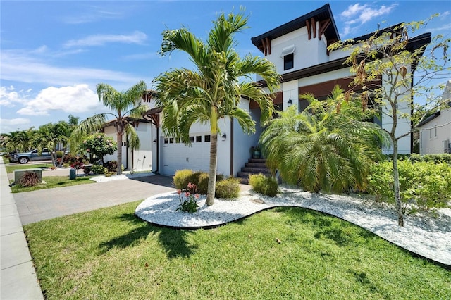 view of front facade with decorative driveway, a garage, a front lawn, and stucco siding