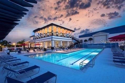 pool at dusk with a community pool and a patio