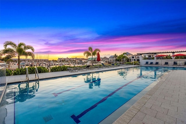 pool at dusk with a community pool and a patio area