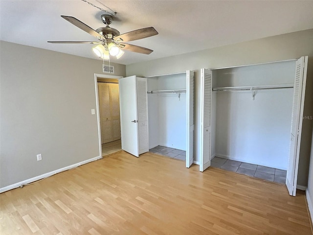 1001 77th Ave N Unit 206, Saint Petersburg, FL 33702 - unfurnished bedroom with visible vents, baseboards, light wood finished floors, two closets, and a ceiling fan