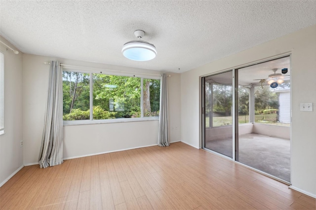spare room with wood finished floors, a textured ceiling, and baseboards