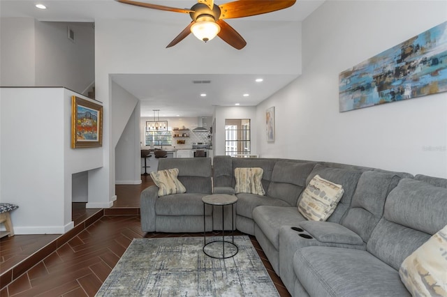 living area with wood finished floors, visible vents, baseboards, and ceiling fan with notable chandelier
