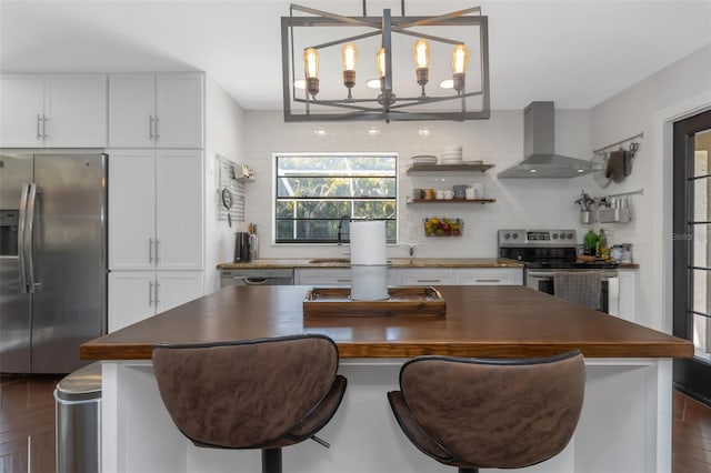 kitchen featuring dark countertops, wall chimney exhaust hood, appliances with stainless steel finishes, and decorative backsplash