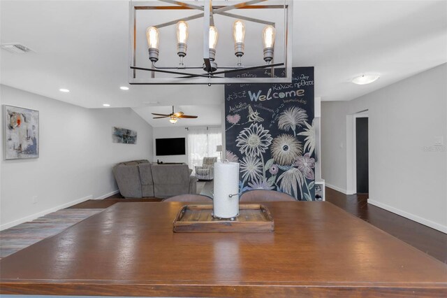 dining space featuring ceiling fan with notable chandelier, visible vents, wood finished floors, and baseboards